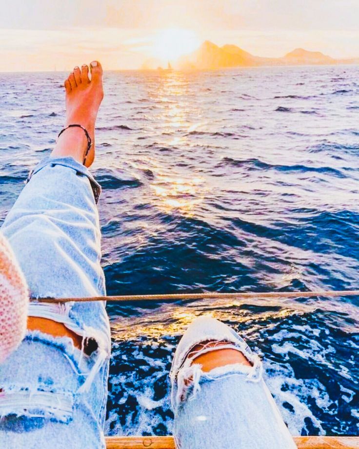 a person sitting on the back of a boat with their feet up in the air