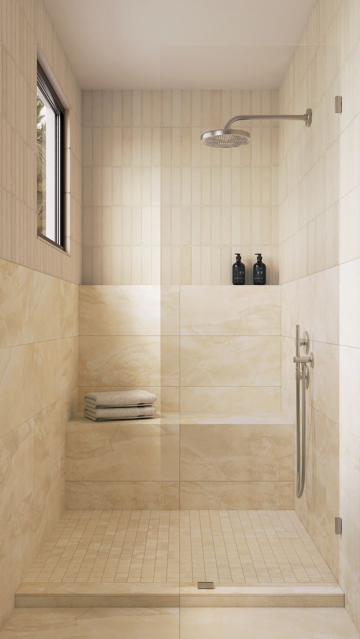 a white tiled bathroom with shower and window