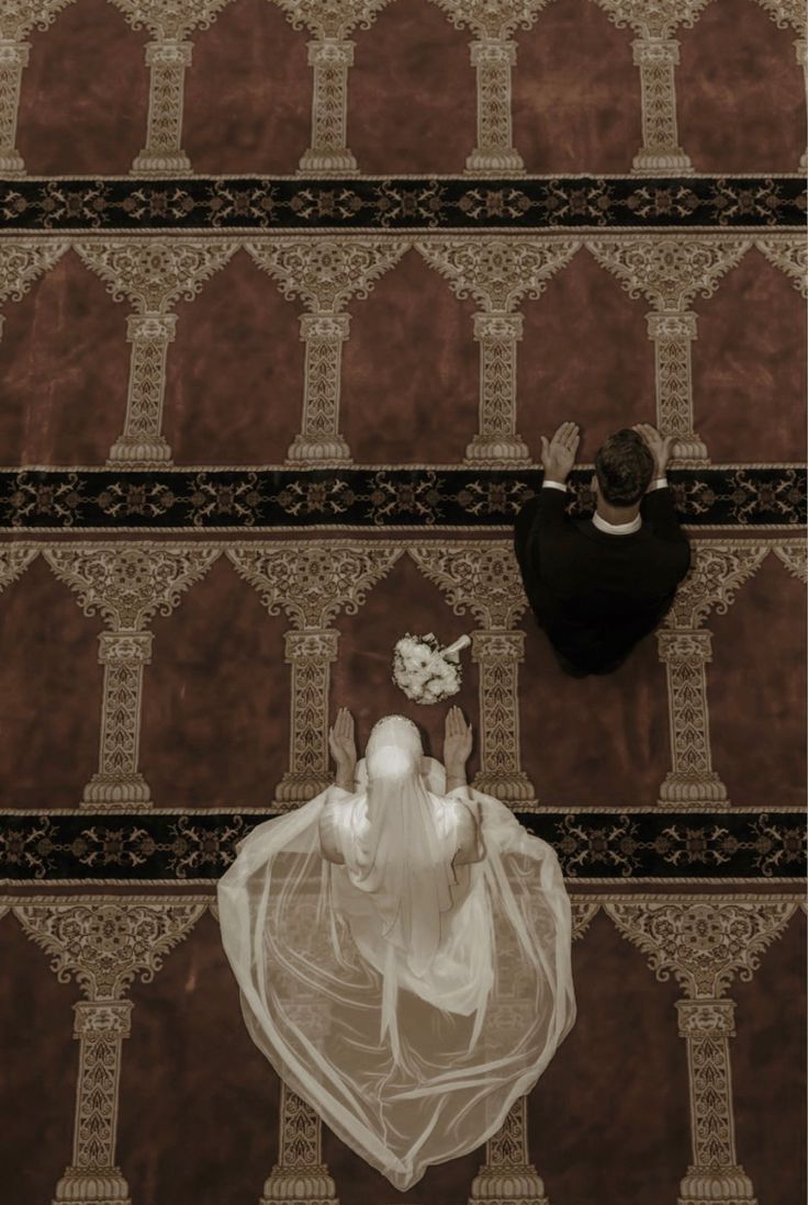 a bride and groom standing on the floor in front of an intricately designed wall