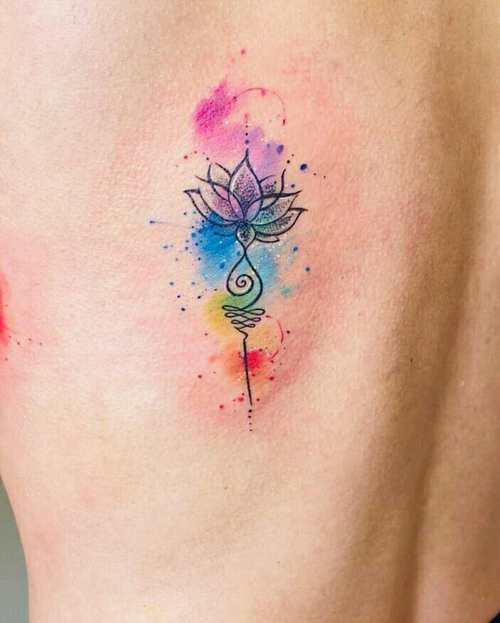 a woman's back with a watercolor tattoo design on her lower side belly