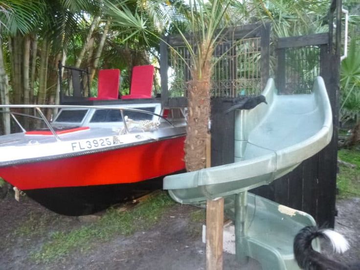 a red and white boat sitting next to a green slide