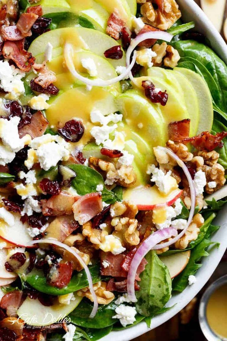 a salad with spinach, apples, cheese and nuts