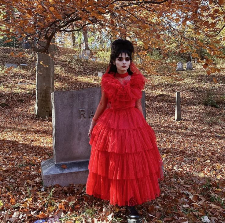 a woman in a red dress standing next to a grave