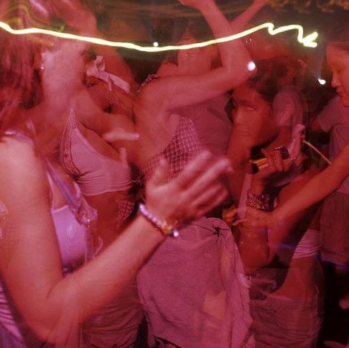 a group of people standing around each other in front of a neon colored light show