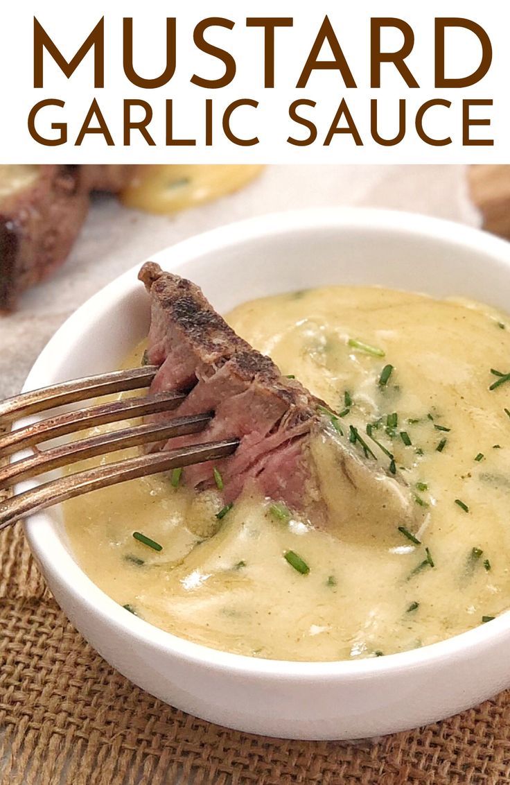 a fork in a white bowl filled with garlic sauce and steak on top of it