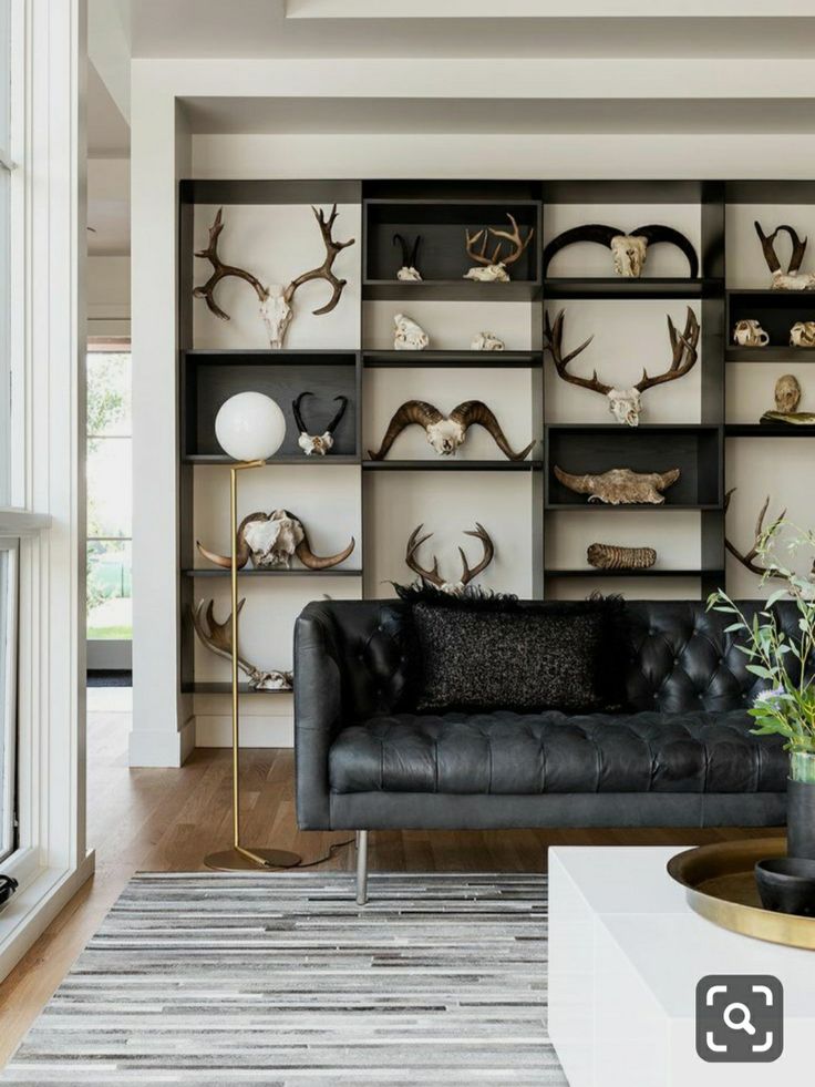 a black leather couch sitting in front of a book shelf filled with antlers on it