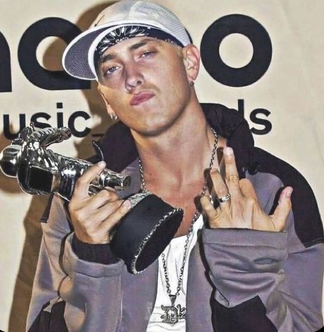 a young man holding up his hands while wearing a baseball cap and silver bracelets