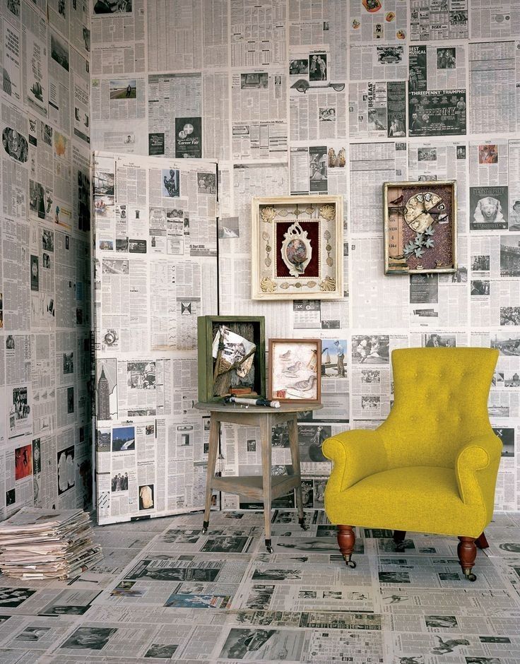 a yellow chair sitting in front of a wall covered with newspaper paper and pictures on it