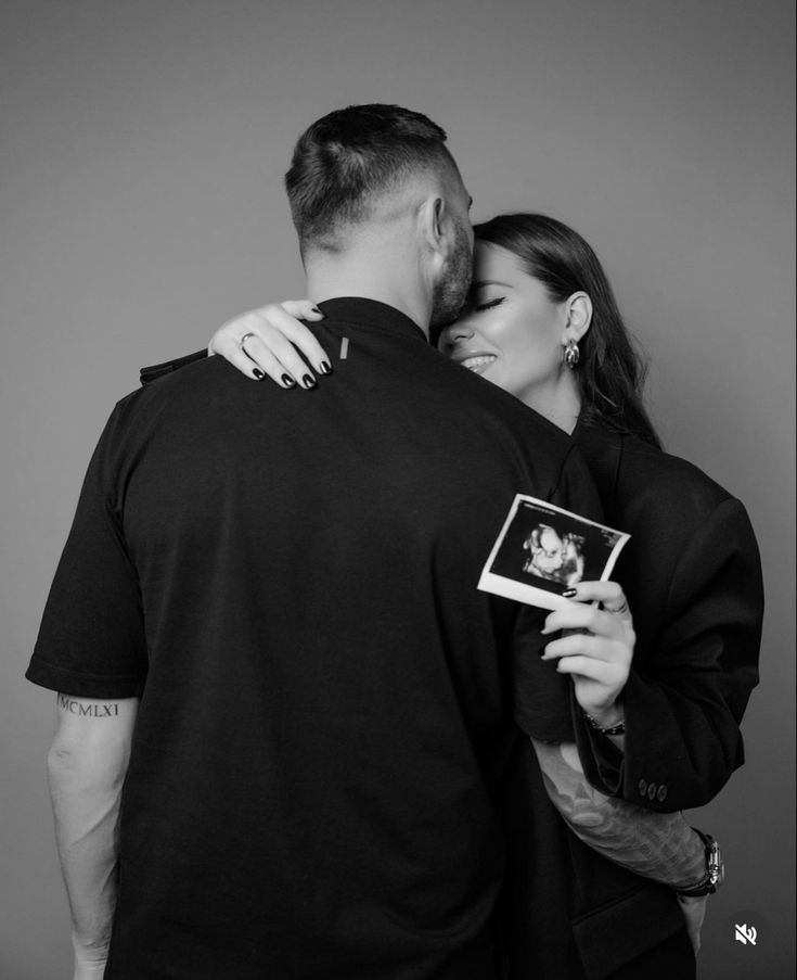 a man and woman embracing each other while holding an object in their hands, with the photo taken from behind them