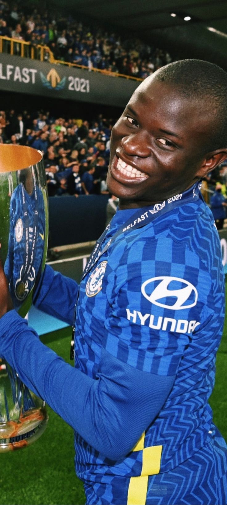 a soccer player holding up a trophy in front of a stadium full of people and fans