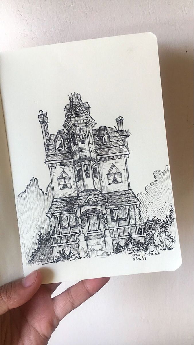 a hand holding up a drawing of a house