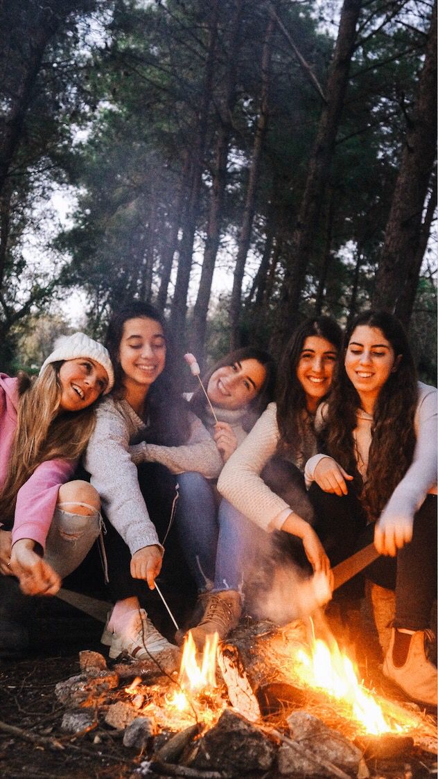 group of young women sitting around a campfire