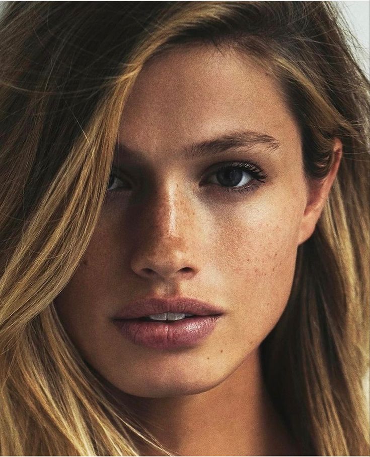 a close up of a woman with freckles on her face and long hair