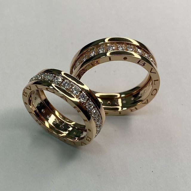 two gold wedding rings with diamonds on each one and the word love spelled in cursive writing