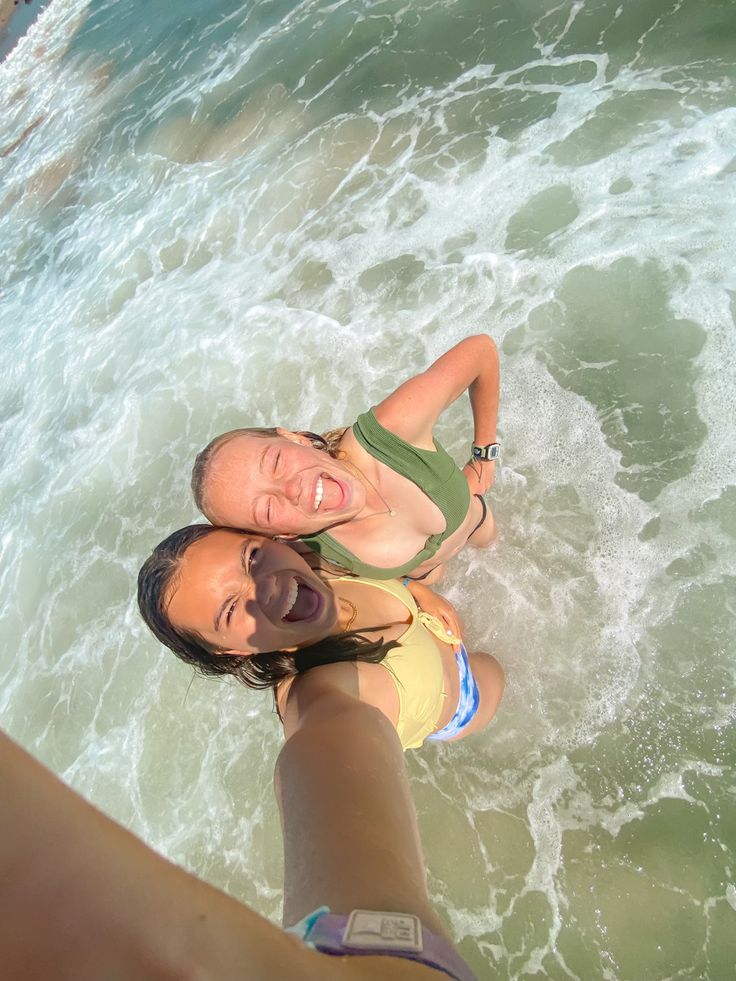 two women are standing in the water and one is holding her arm around the other