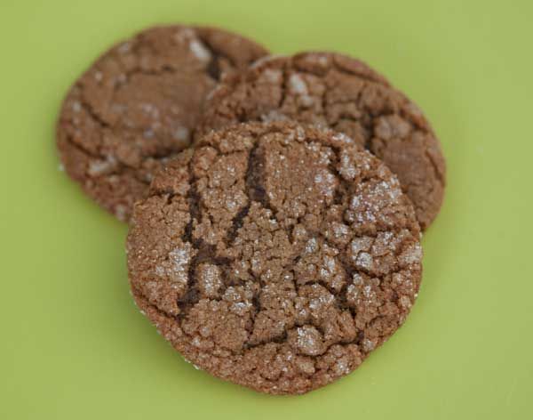 three chocolate cookies sitting on top of a green table