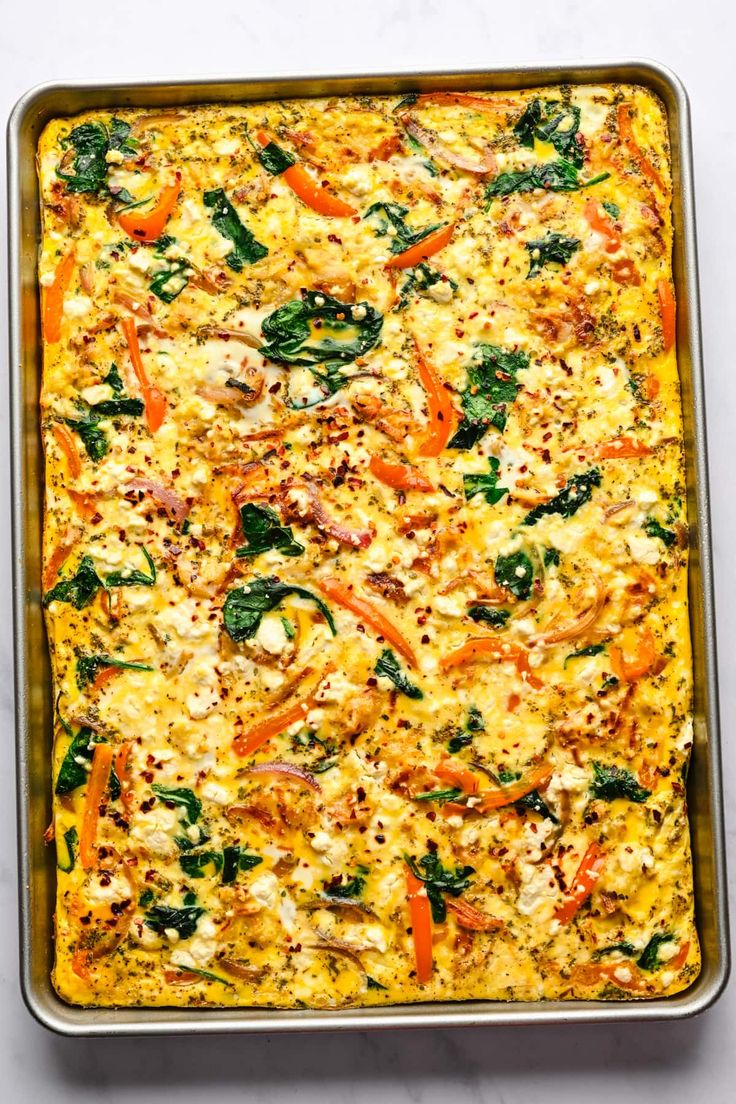 a casserole dish filled with vegetables and cheese on a white counter top, ready to be eaten