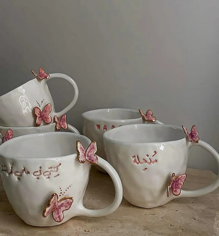 four white coffee cups with pink butterflies on them