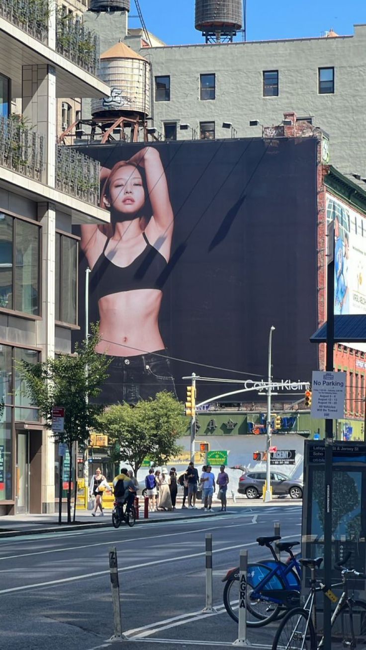 a large advertisement on the side of a building in an urban area with people walking around