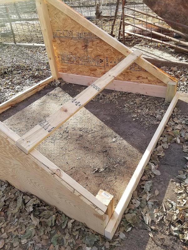 a wooden bed frame laying on top of some dirt and wood chips in an enclosure