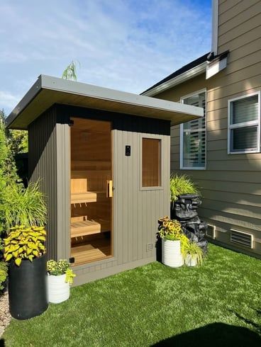 a backyard with a shed and potted plants on the grass in front of it