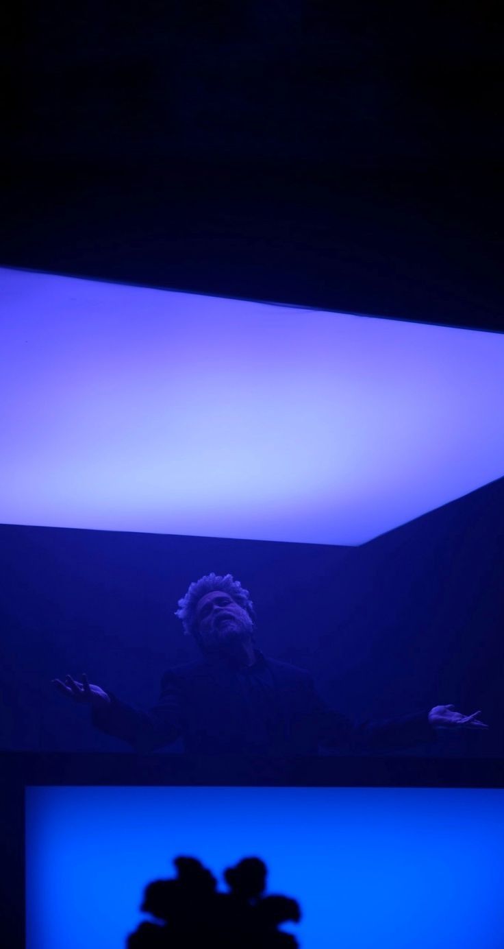 a vase with flowers in it sitting next to a blue light filled wall and ceiling