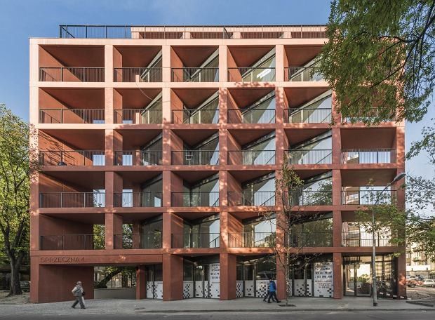 an orange building with many balconies on the side and people walking by it