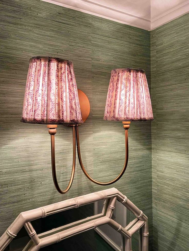 two lamps are on the wall next to a mirror