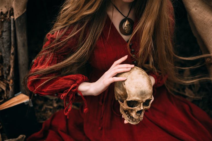 a woman in a red dress holding a skull