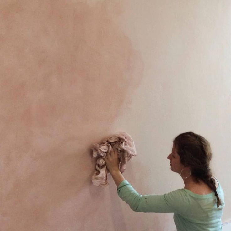 a woman painting a wall with pink paint