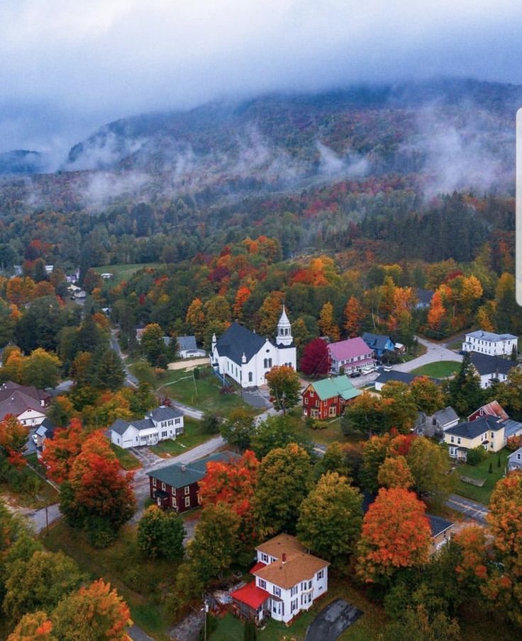 an aerial view of a small town surrounded by trees in the fall with colorful foliage