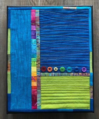 a quilted table runner with buttons and strips on the edge, sitting on top of a wooden surface