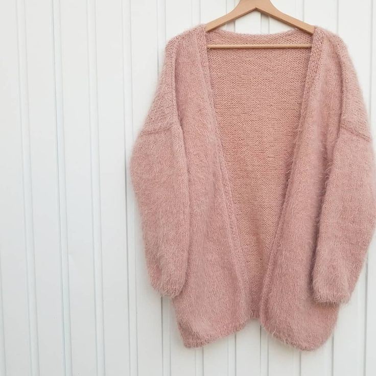 a pink cardigan hanging on a white wall