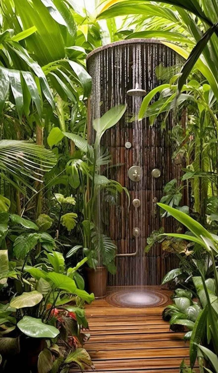 an outdoor shower surrounded by tropical plants and greenery in a garden setting with wooden steps leading up to it