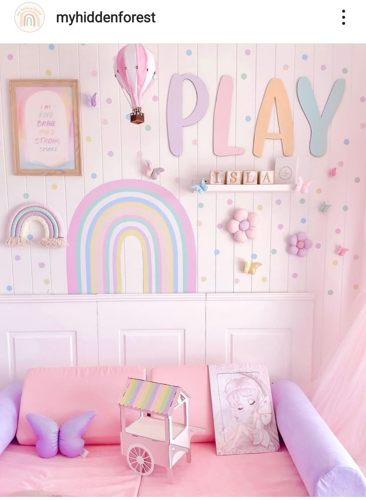 there is a pink couch in the room with rainbows on the wall and pictures above it