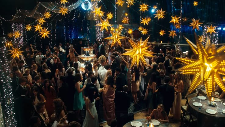 a large group of people standing around each other in front of a stage with stars on it