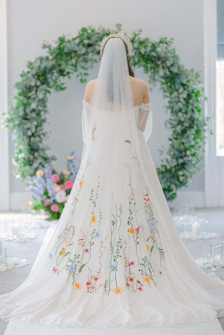 the back of a bride's wedding dress in front of a floral arch with greenery