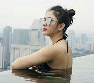 a woman wearing sunglasses sitting on top of a swimming pool in the middle of a city