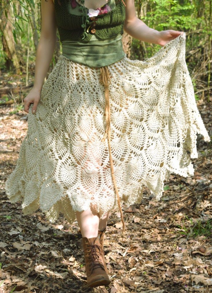 a woman walking through the woods wearing a crochet skirt