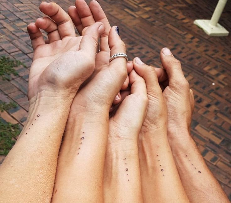 four people holding hands with small dots on their fingers