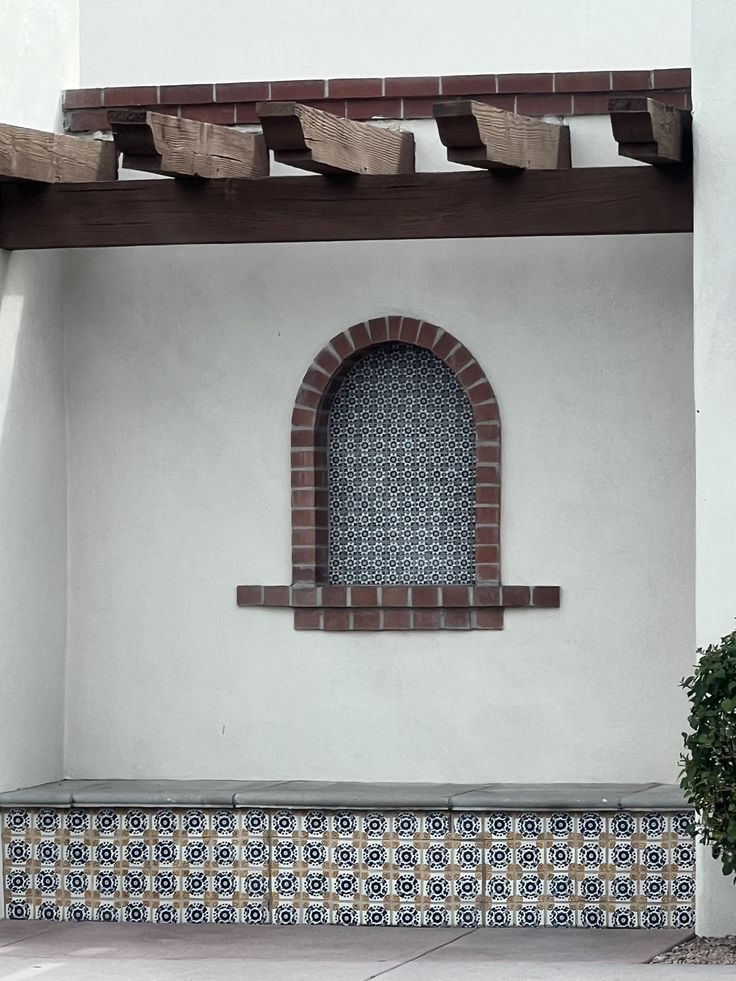 an arched window on the side of a white building with blue and black tile around it