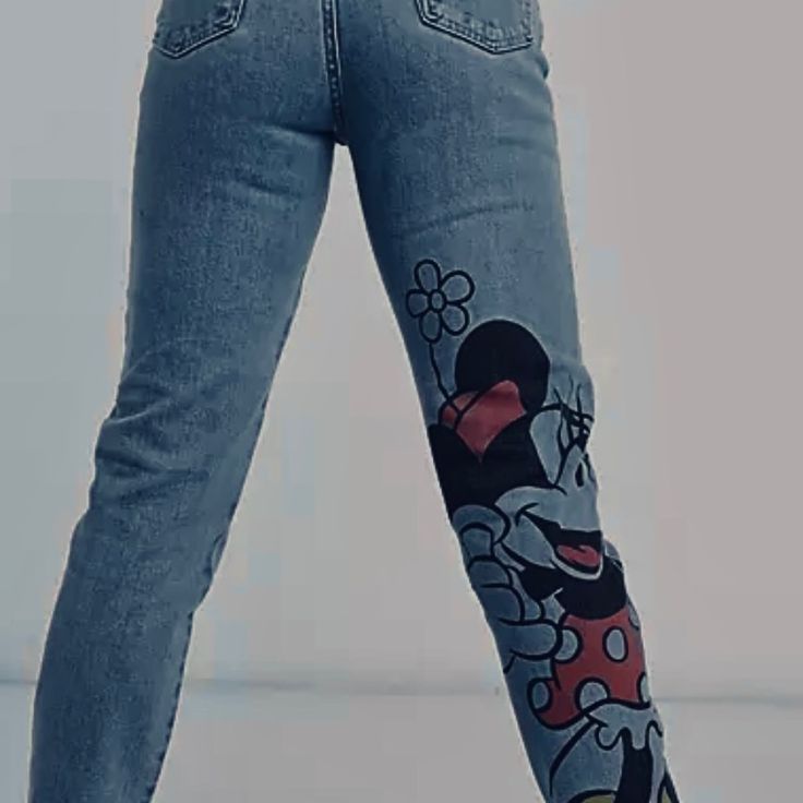 the legs of a woman with mickey mouse tattoos on her leggings and jeans