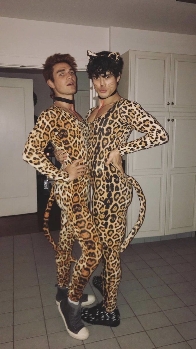 two people dressed up as cats and leopards in the middle of a kitchen with white cabinets