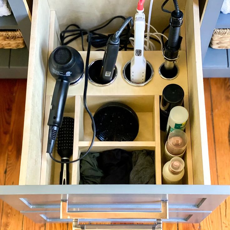 an open drawer with hair dryers and other items