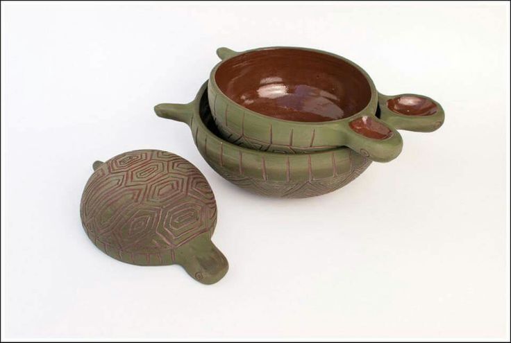 two brown and green pottery items sitting on a white surface with one turtle shaped bowl next to the other