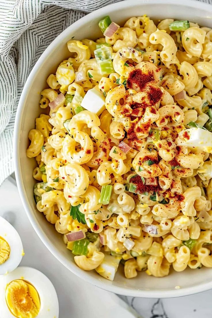 a white bowl filled with macaroni salad next to an egg on the side