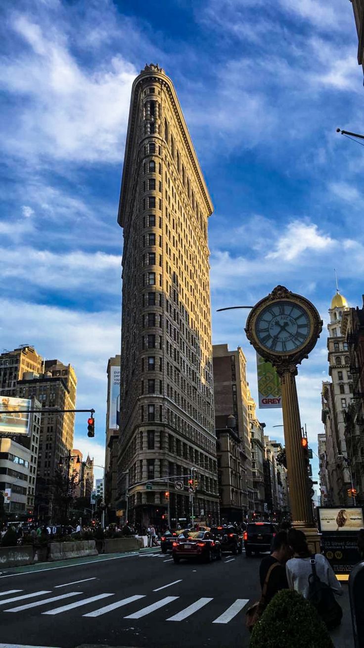 a city street with tall buildings and a clock