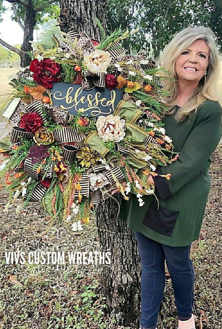 a woman standing next to a tree holding a sign that says, elli's custom wreaths