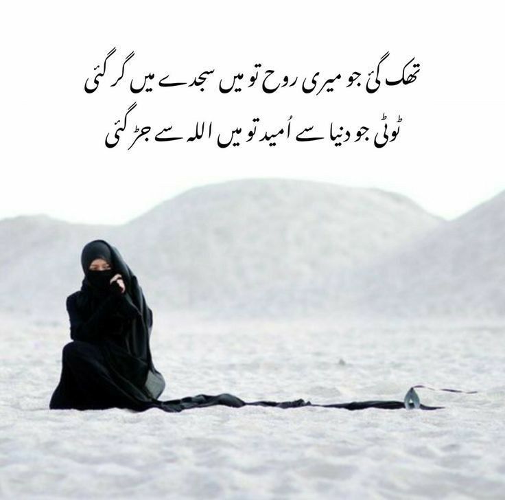 a woman sitting in the sand with her head covered by a black shawl and looking up