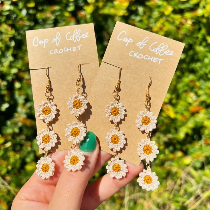 two pairs of earrings with daisies hanging from them